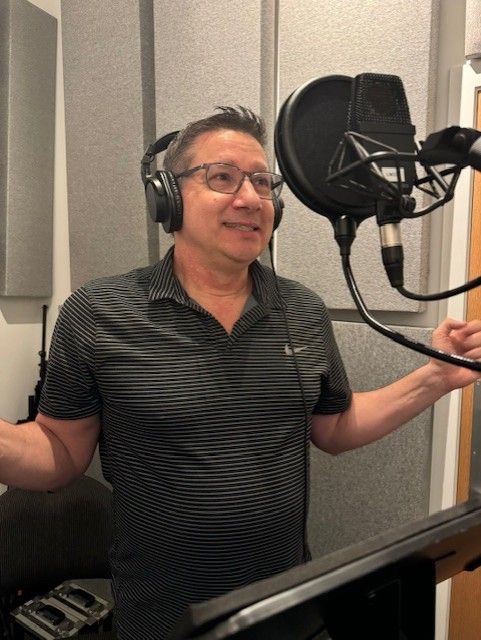 Voice actor recording in a studio, wearing headphones and glasses